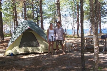 a couple and a dog at a campsite